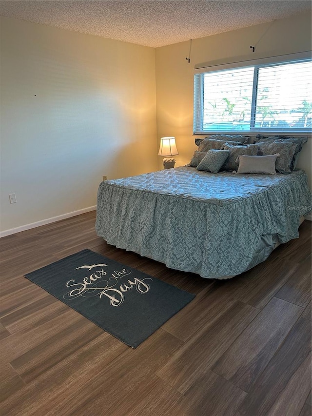 bedroom with wood finished floors, baseboards, and a textured ceiling