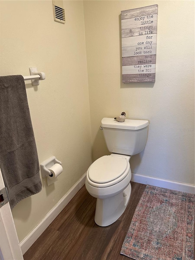 bathroom with toilet, wood finished floors, visible vents, and baseboards