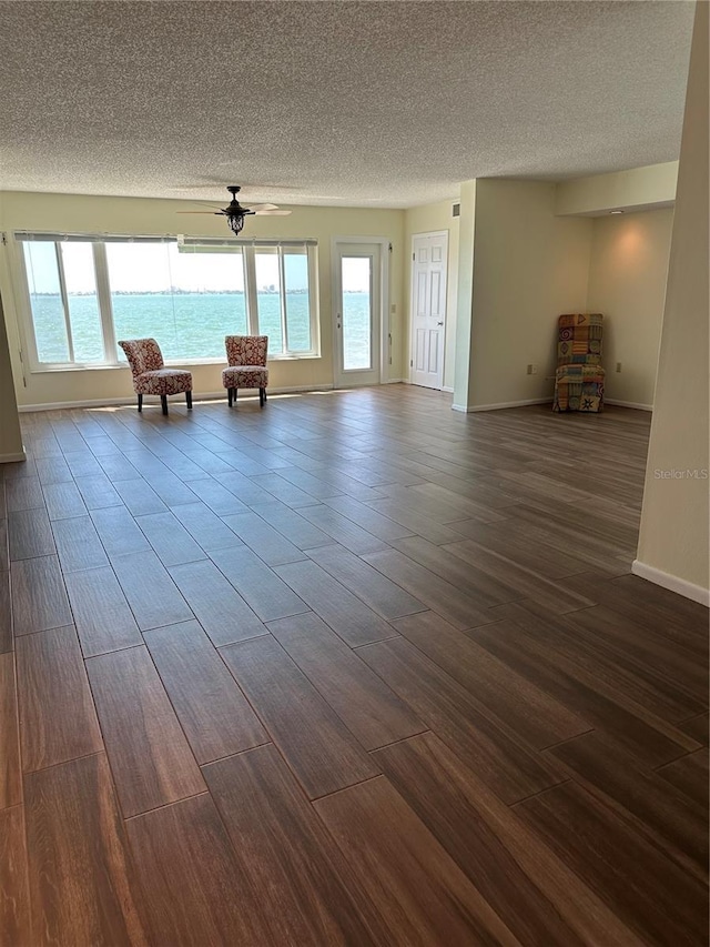 interior space with baseboards, dark wood-type flooring, a ceiling fan, and a textured ceiling