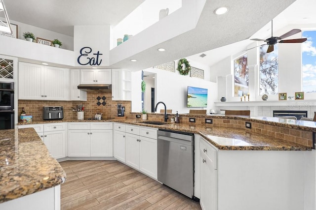 kitchen with dark stone countertops, white cabinetry, dishwasher, and sink