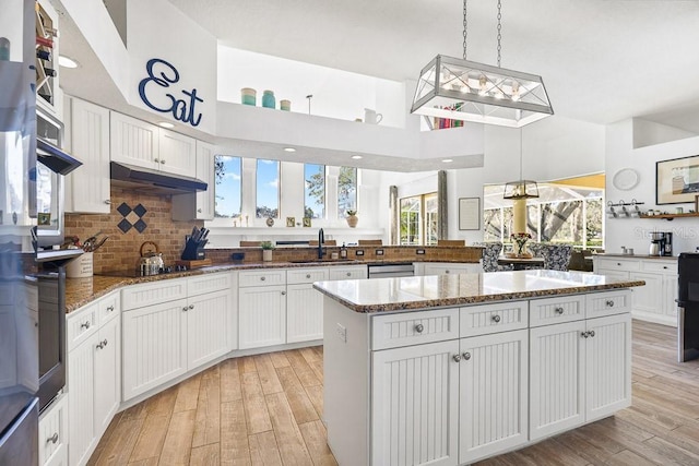 kitchen featuring white cabinets, a kitchen island, hanging light fixtures, and light hardwood / wood-style flooring