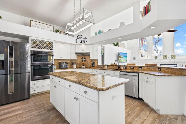 kitchen featuring appliances with stainless steel finishes, sink, dark stone countertops, white cabinets, and a kitchen island