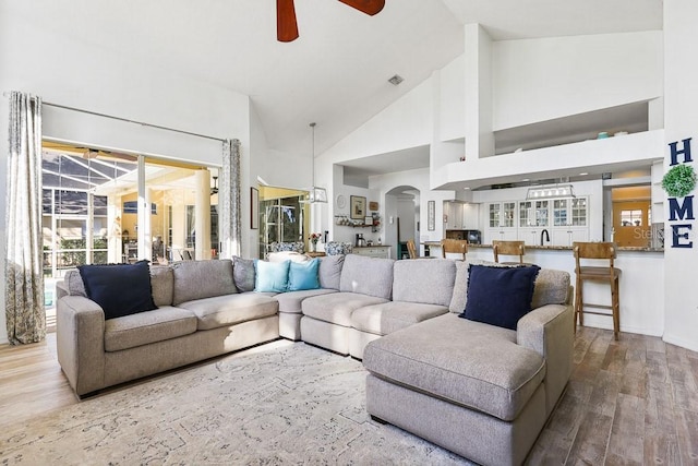 living room with ceiling fan, sink, high vaulted ceiling, and hardwood / wood-style flooring