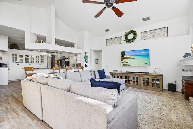 living room featuring ceiling fan, high vaulted ceiling, and light hardwood / wood-style floors