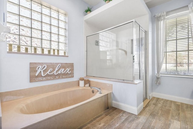 bathroom with hardwood / wood-style floors, shower with separate bathtub, and a wealth of natural light