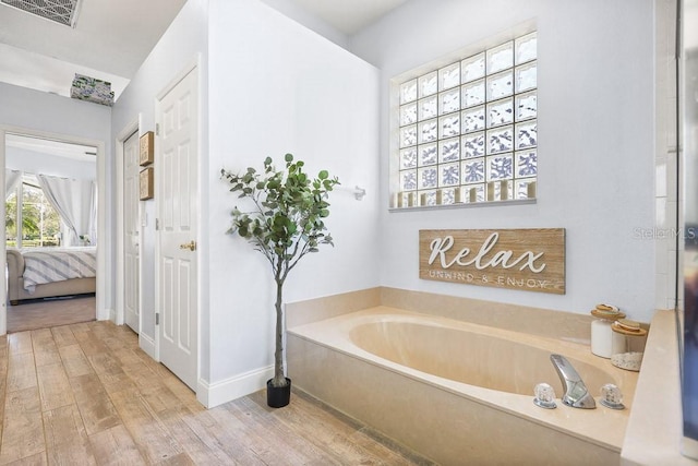 bathroom with hardwood / wood-style flooring and a tub