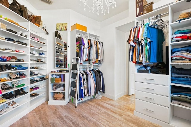 walk in closet featuring a notable chandelier and light hardwood / wood-style floors