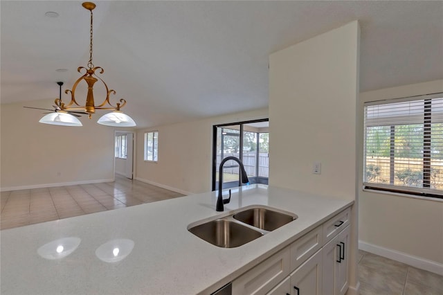 kitchen with light stone countertops, sink, pendant lighting, light tile patterned floors, and white cabinetry