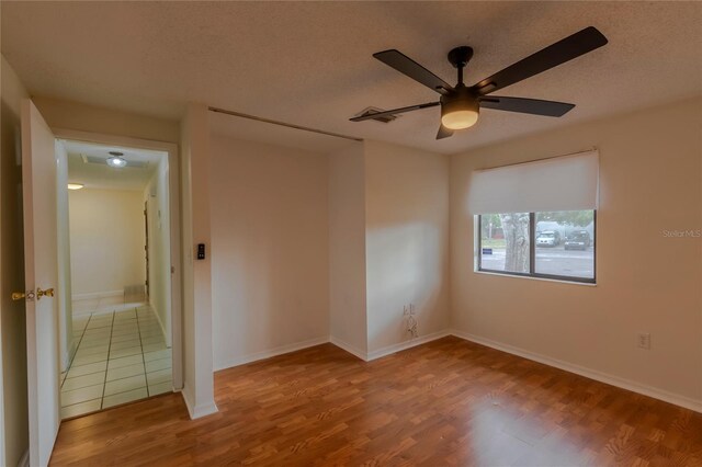 empty room featuring ceiling fan, a textured ceiling, and hardwood / wood-style flooring