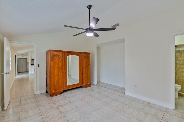 unfurnished bedroom featuring ensuite bathroom, light tile patterned floors, ceiling fan, and lofted ceiling