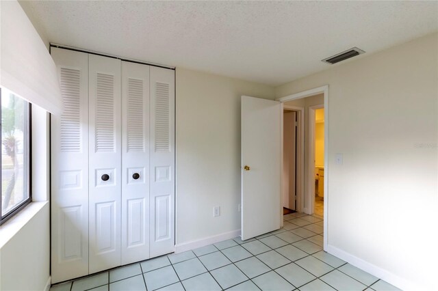 unfurnished bedroom with a closet, light tile patterned floors, and a textured ceiling