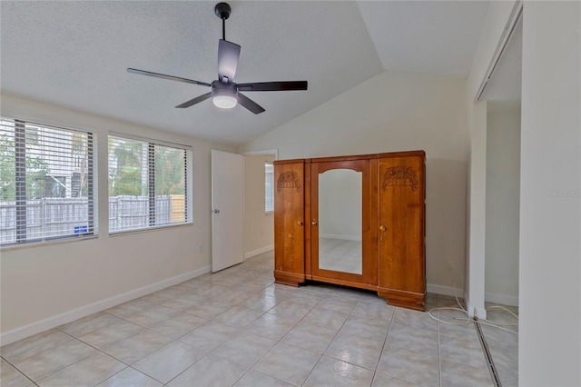 tiled spare room featuring ceiling fan, a textured ceiling, and vaulted ceiling