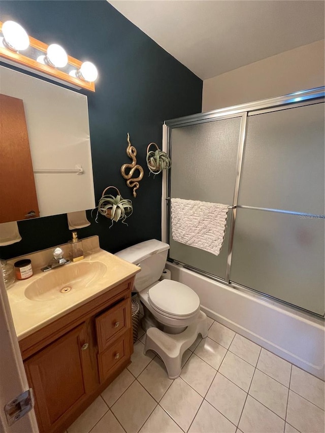 full bathroom featuring combined bath / shower with glass door, vanity, tile patterned floors, and toilet