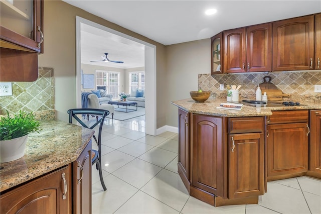 kitchen featuring ceiling fan, light tile patterned flooring, light stone counters, and decorative backsplash