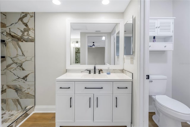 bathroom with ceiling fan, walk in shower, toilet, vanity, and hardwood / wood-style flooring