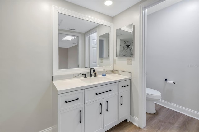 bathroom featuring vanity, wood-type flooring, and toilet