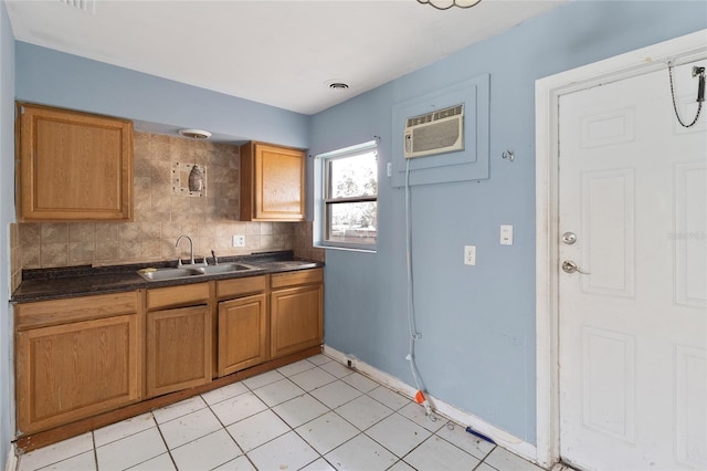 kitchen with a sink, an AC wall unit, dark countertops, tasteful backsplash, and brown cabinetry
