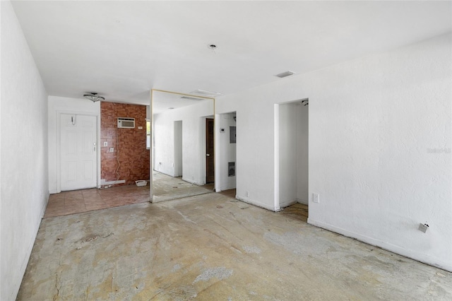 spare room with concrete flooring and an AC wall unit