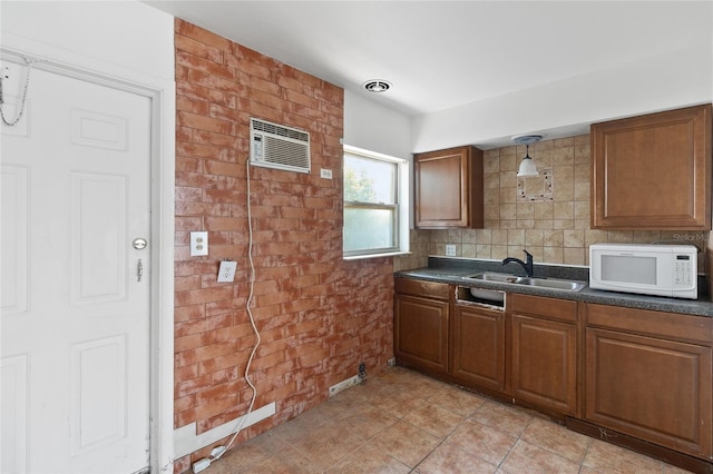 kitchen featuring white microwave, a sink, dark countertops, brown cabinets, and decorative light fixtures