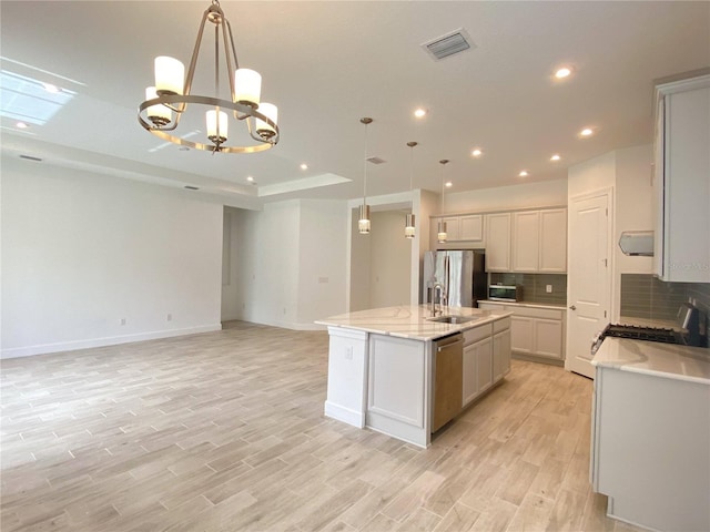 kitchen with a notable chandelier, decorative light fixtures, an island with sink, and appliances with stainless steel finishes