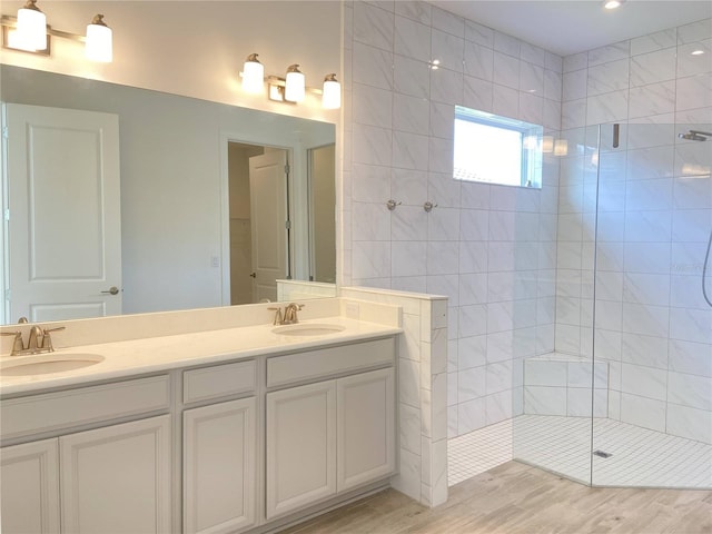 bathroom with vanity, wood-type flooring, and tiled shower