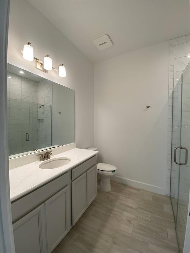 bathroom featuring vanity, toilet, and an enclosed shower