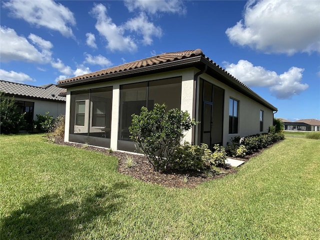 view of home's exterior with a sunroom and a lawn