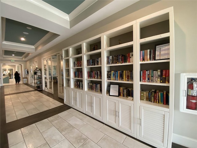 corridor with light tile patterned flooring and a tray ceiling