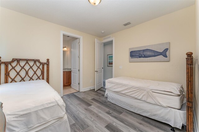 bedroom featuring light wood-type flooring and ensuite bath