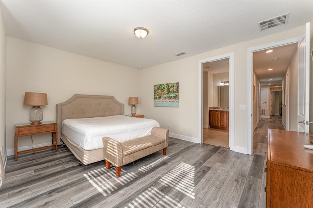 bedroom with ensuite bathroom and dark hardwood / wood-style floors