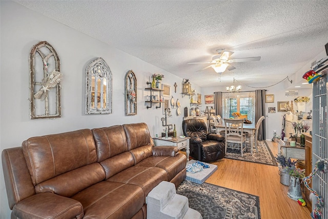 living room featuring ceiling fan with notable chandelier, a textured ceiling, and hardwood / wood-style flooring