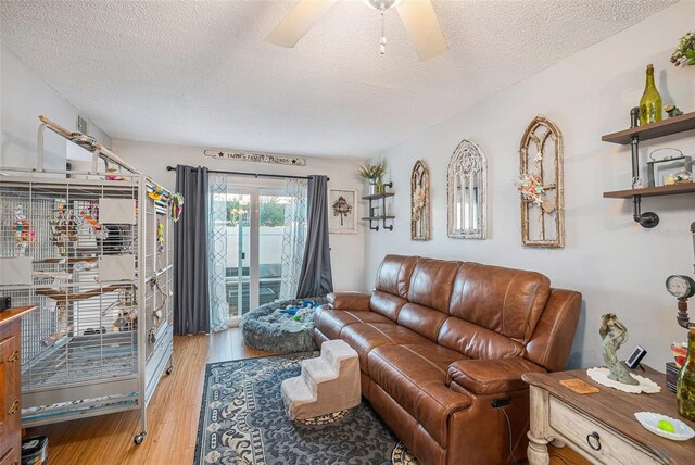 living room with a textured ceiling, light hardwood / wood-style flooring, and ceiling fan