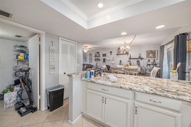 kitchen featuring white cabinets, light stone counters, crown molding, light tile patterned floors, and ceiling fan with notable chandelier