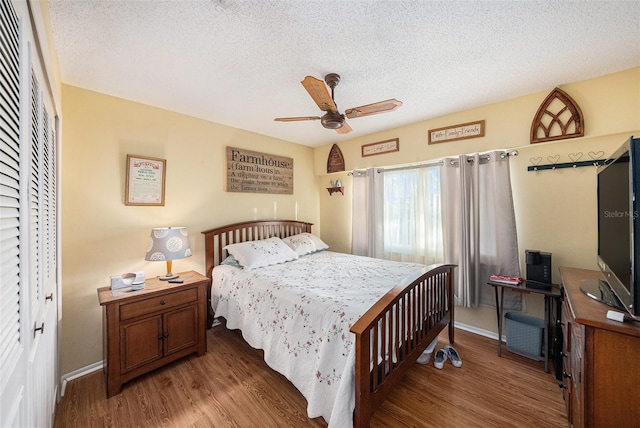 bedroom with ceiling fan, dark hardwood / wood-style floors, a textured ceiling, and a closet