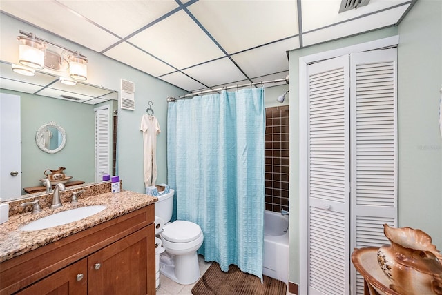 full bathroom with a drop ceiling, vanity, tile patterned flooring, toilet, and shower / tub combo