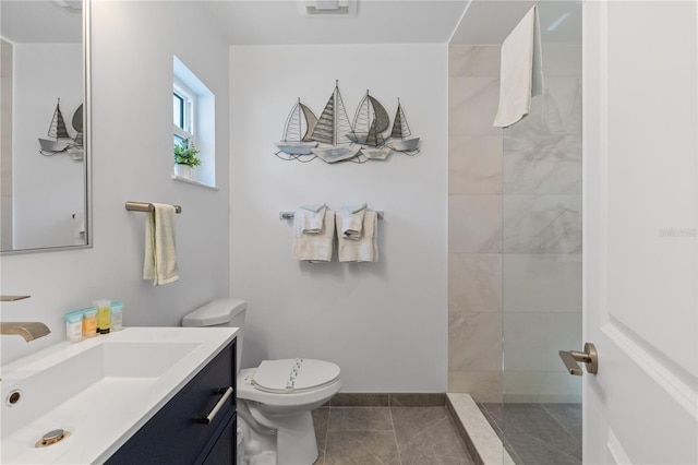 bathroom featuring tiled shower, tile patterned flooring, vanity, and toilet