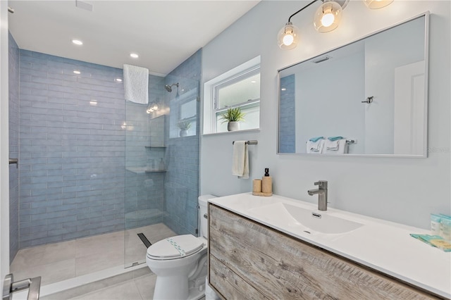 bathroom with toilet, tile patterned flooring, tiled shower, and vanity