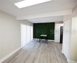 hall with beamed ceiling and light hardwood / wood-style flooring