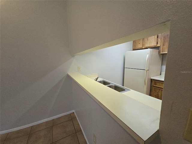 kitchen with tile patterned flooring, white fridge, and sink