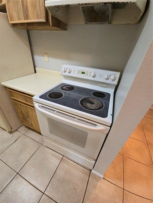 kitchen featuring exhaust hood, light tile patterned flooring, and white electric range oven