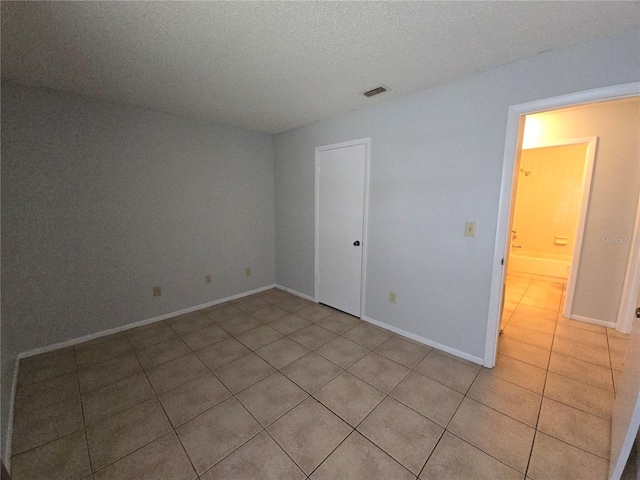 spare room featuring light tile patterned floors and a textured ceiling