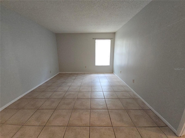 tiled empty room with a textured ceiling