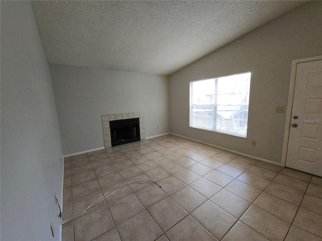 unfurnished living room with light tile patterned flooring, vaulted ceiling, a textured ceiling, and a tiled fireplace