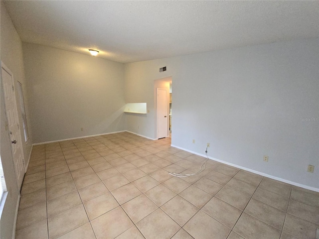 spare room featuring lofted ceiling and light tile patterned floors