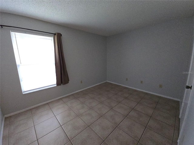 tiled empty room featuring a textured ceiling