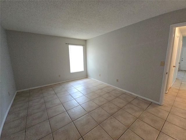 empty room featuring light tile patterned flooring and a textured ceiling