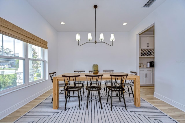 dining area with light hardwood / wood-style floors and a notable chandelier