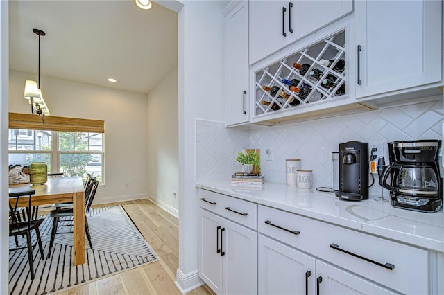 kitchen featuring white cabinets, tasteful backsplash, light hardwood / wood-style flooring, and hanging light fixtures