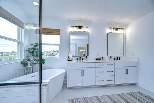 bathroom with tile patterned floors, vanity, a bath, and a wealth of natural light