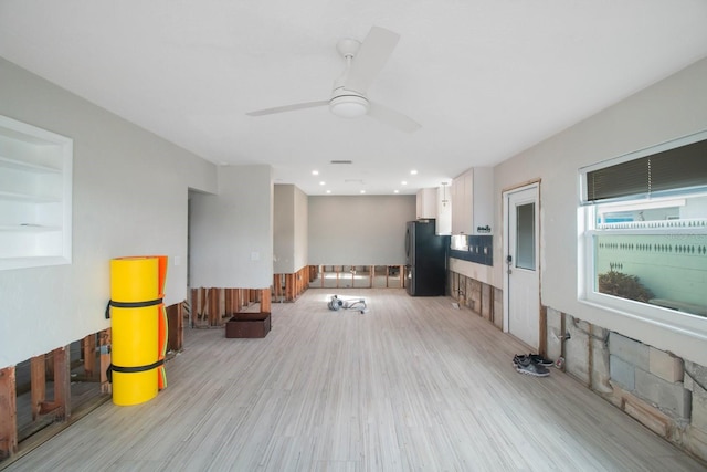 living room featuring built in shelves, ceiling fan, and light wood-type flooring